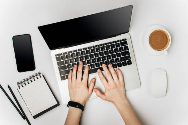 istock hands on the laptop keyboard, cup with coffee, notebook, phone and pencils 1160015256