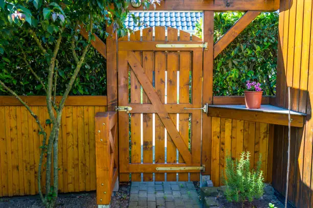 Photo of Wooden gate and fence on the back of the home garden. The gate is closed with a padlock.