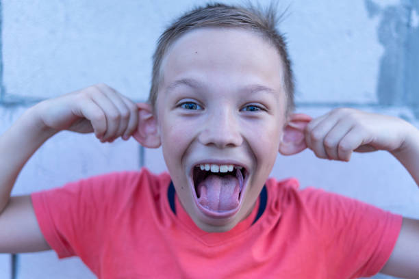 istock A 10-year-old boy holds his ears, depicting a monkey. 1160019368