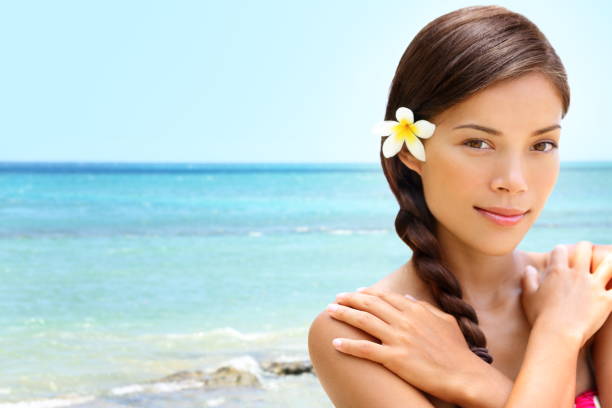 Beach wellness spa beauty woman on Hawaii beach. Beautiful serene and peaceful young mixed race Asian Caucasian female model relaxing on holiday travel resort. Flower in dark braided hair.