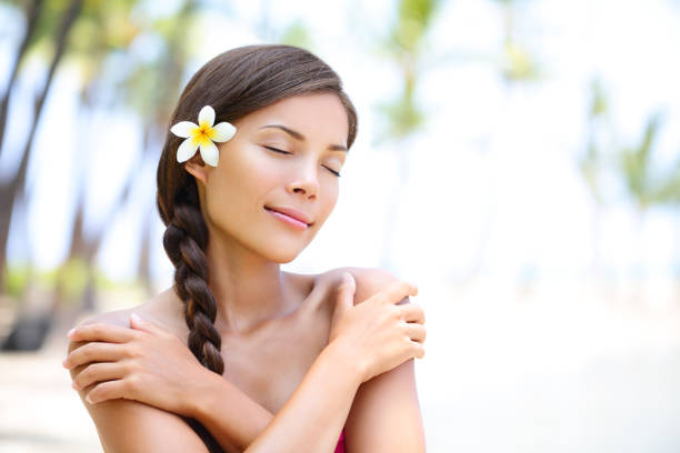 Spa wellness beach beauty woman relaxing with eyes closes on Hawaii beach. Beautiful serene and peaceful young mixed race Asian Caucasian female model on holiday travel resort. Flower in braided hair.
