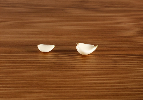 Garlic pieces on wooden background.