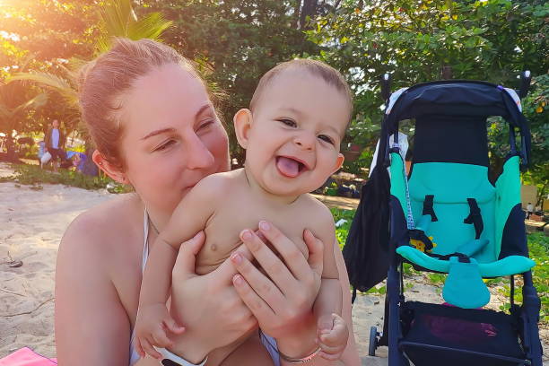 Happy mother and baby on the sandy beach near the travel strolle Happy mother and baby on the sandy beach near the travel stroller outing tantarum in babies stock pictures, royalty-free photos & images