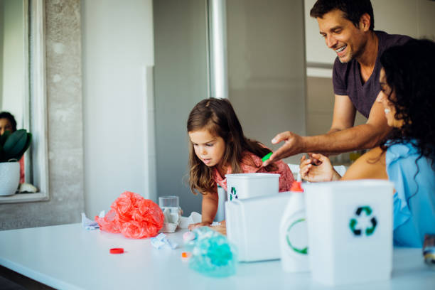 happy parents teaching daughter to recycle - sustainable resources environment education cleaning imagens e fotografias de stock