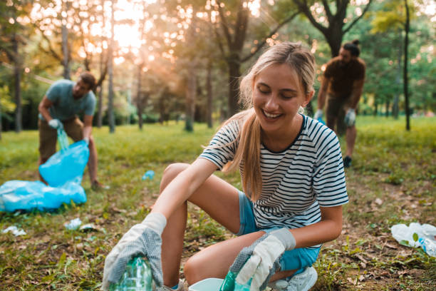 молодая женщина утилизации бутылок - sustainable resources environment education cleaning стоковые фото и изображения