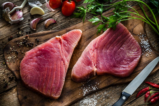 two raw tuna steaks on rustic wooden table - tuna imagens e fotografias de stock
