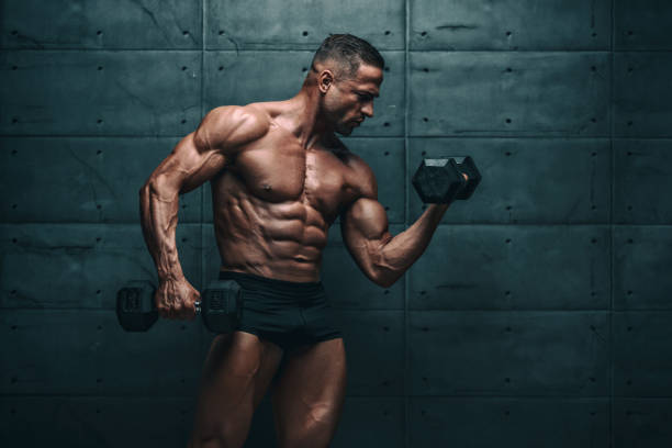istock Muscular Men Exercise With Weights. He is performing biceps curls with dumbbels 1160031946