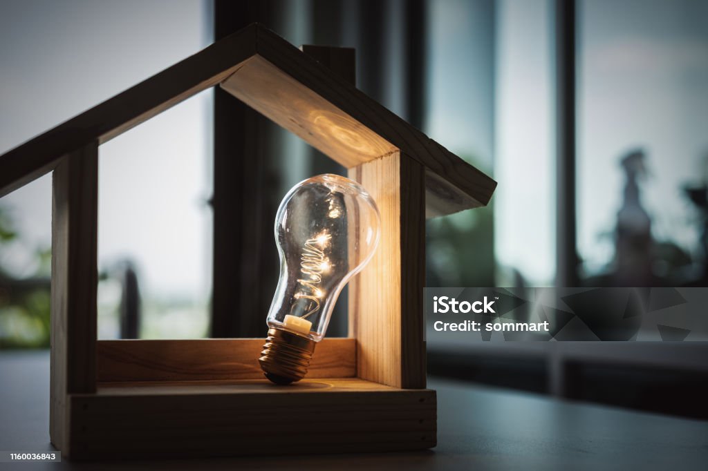 Light bulb with wood house on the table, a symbol for construction, Creative light bulb idea, power energy or business idea concept ecology, loan, mortgage, property or home. Fuel and Power Generation Stock Photo