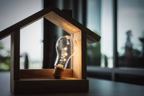 Light bulb with wood house on the table, a symbol for construction, Creative light bulb idea, power energy or business idea concept ecology, loan, mortgage, property or home. stock photo