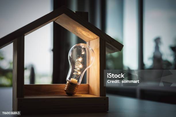 Light Bulb With Wood House On The Table A Symbol For Construction Creative Light Bulb Idea Power Energy Or Business Idea Concept Ecology Loan Mortgage Property Or Home Stock Photo - Download Image Now