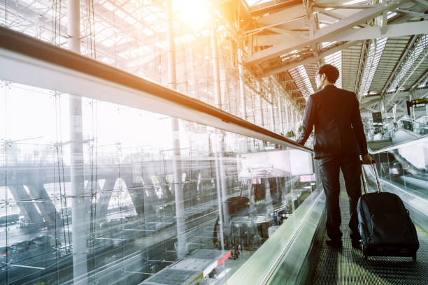 istock Businessman checking e-mail on mobile phone while walking with suitcase inside airport 1160036942