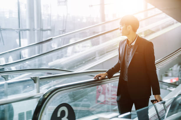 istock Businessman checking e-mail on mobile phone while walking with suitcase inside airport 1160036945