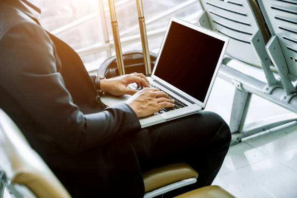 istock Businessman checking e-mail on mobile phone while walking with suitcase inside airport 1160036954