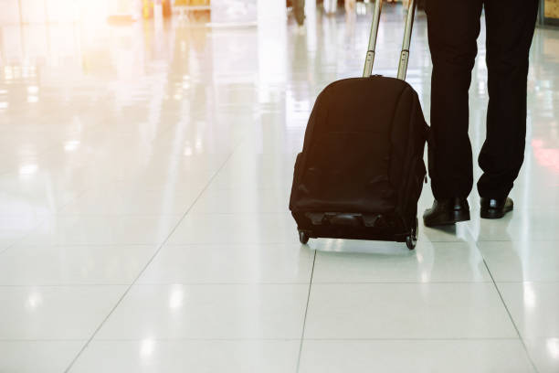 istock Businessman checking e-mail on mobile phone while walking with suitcase inside airport 1160036991