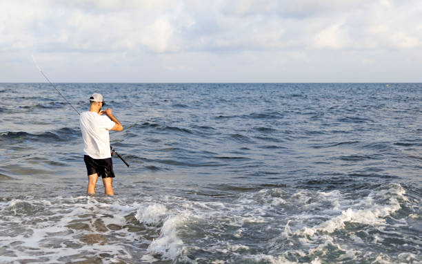istock Fisherman standing at the seashore hooks a fish. 1160037088