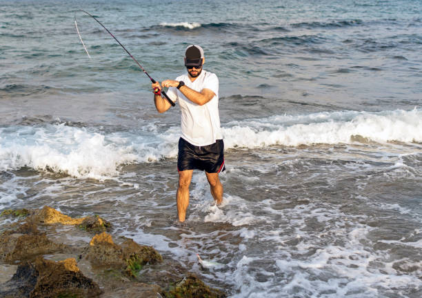 istock Fisherman standing at the seashore hooks a fish. 1160037129