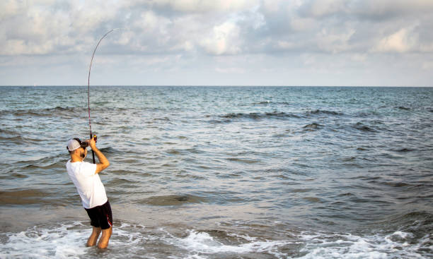 istock Fisherman standing at the seashore hooks a fish. 1160037134