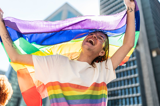 Happy man celebrating with rainbow flag during the LGBTQI parade in Sao Paulo