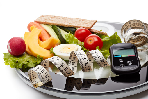 Still life with healthy food, scales, measuring tape and blood glucose meter on white background. Concept: control of level glucose. Healthy lifestyle, healthy food, slimming