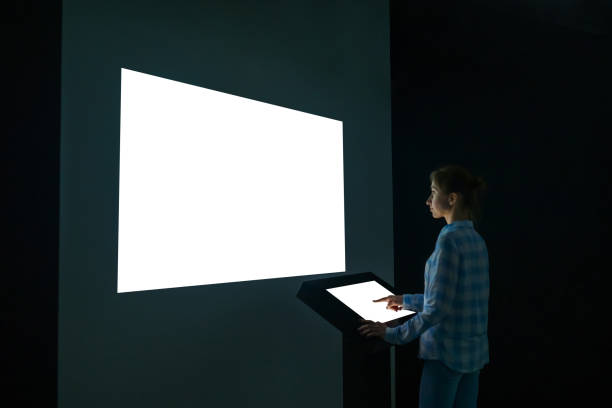 Woman looking at white blank large interactive wall display - mockup image