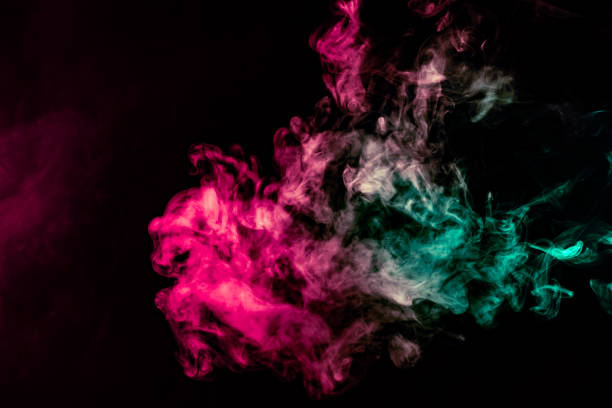 istock Colored background with winding clouds of smoke from patterns of different forms of pink, green and blue colors with tongues of flame on a black isolated background 1160040535