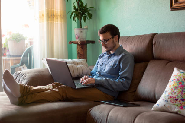 istock Young man with laptop on sofa at home 1160043620