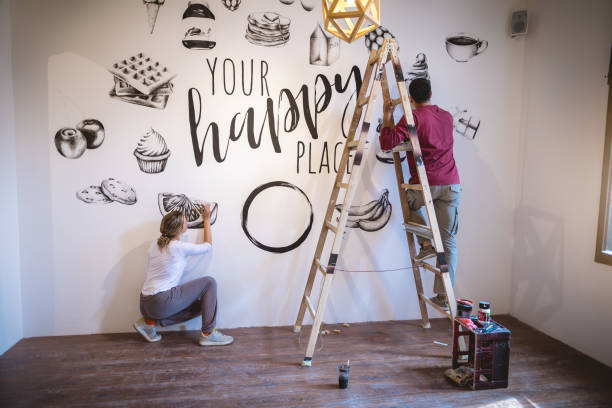 istock Focused couple of painters working on a wall 1160043633
