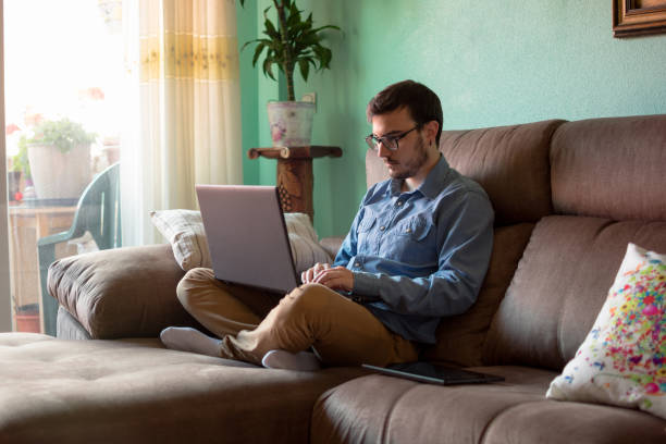 istock Young man with laptop on sofa at home 1160043647