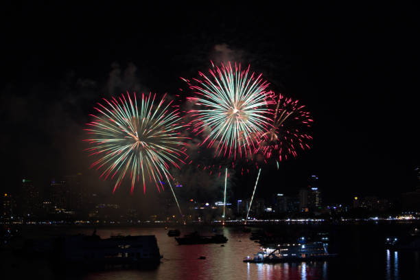istock red green fireworks on beach and reflection color on water surface 1160044864