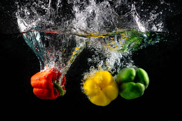 istock Three paprika's falling in the water isolated on black background. 1160045846