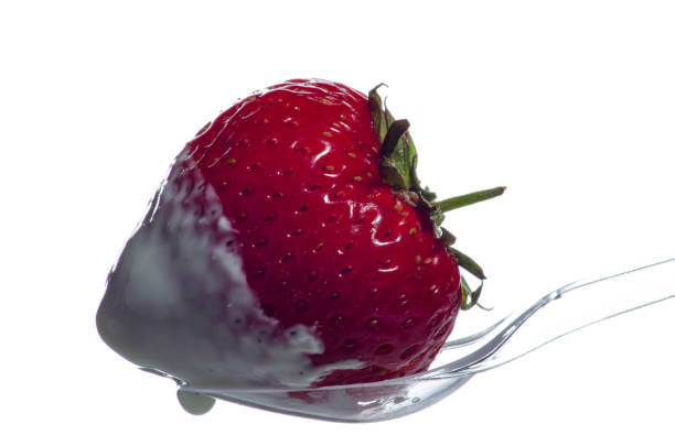 istock Strawberries with cream on a transparent spoon. White background. 1160045922