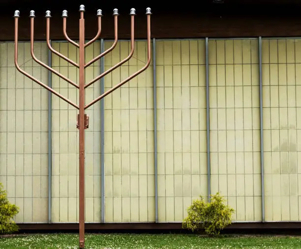 A large medal holiday decortion menorah outside of a temple.