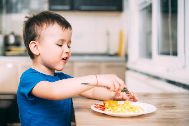 istock a child in a t-shirt in the kitchen eating an omelet, a fork 1160047693