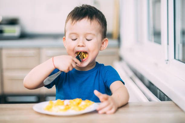 istock a child in a t-shirt in the kitchen eating an omelet, a fork 1160047855