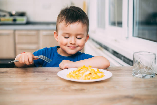 istock a child in a t-shirt in the kitchen eating an omelet, a fork 1160049355
