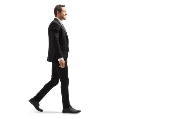 Photo of Young man in a suit walking and smiling