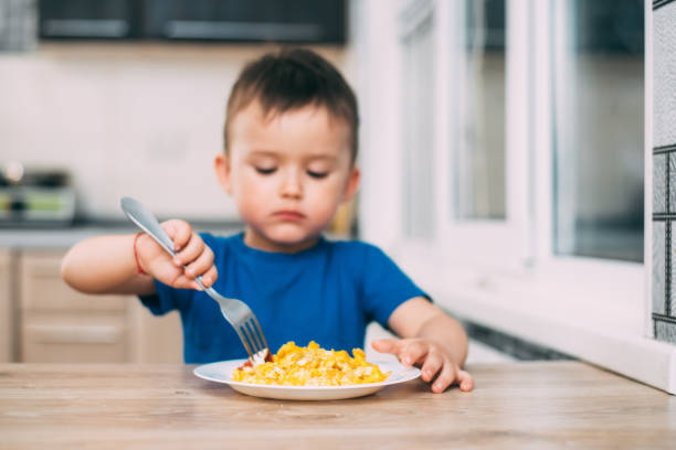 istock a child in a t-shirt in the kitchen eating an omelet, a fork 1160049494