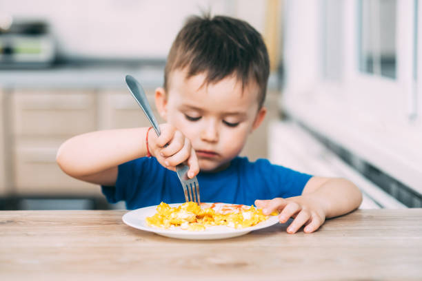 istock a child in a t-shirt in the kitchen eating an omelet, a fork 1160049563