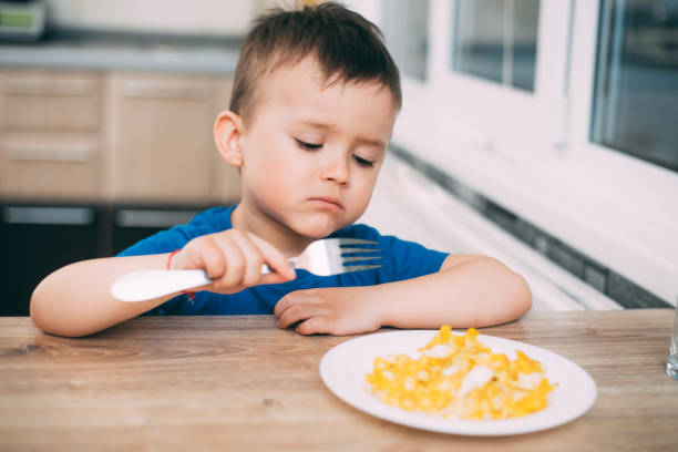 istock a child in a t-shirt in the kitchen eating an omelet, a fork 1160050094