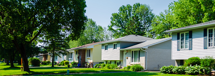 Panorama of sunlit small suburban houses on a tree-lined street in the summer
