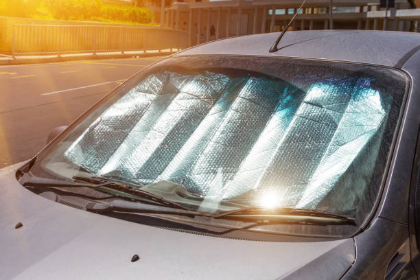 superficie riflettente protettiva sotto il parabrezza dell'autovettura parcheggiata in una giornata calda, riscaldata dai raggi del sole all'interno dell'auto. - parasol foto e immagini stock
