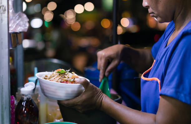 Street food kitchen vendor preparing green papaya salad food for customers at night stock photo