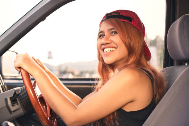 Happy diverse lifestyle millennial Asian woman smiling while driving car in summer sun stock photo