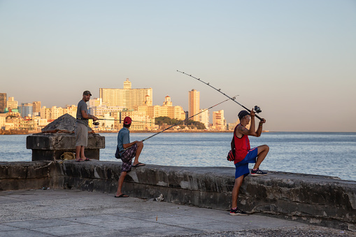 Havana, Cuba - May 21, 2019: Cuban people are fishing in the ocean during a sunny morning sunrise, taken during the Shortage of Food Crisis.