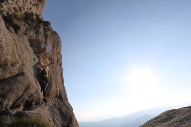 istock Young woman climbs steep rock face above distant hills 1160057839
