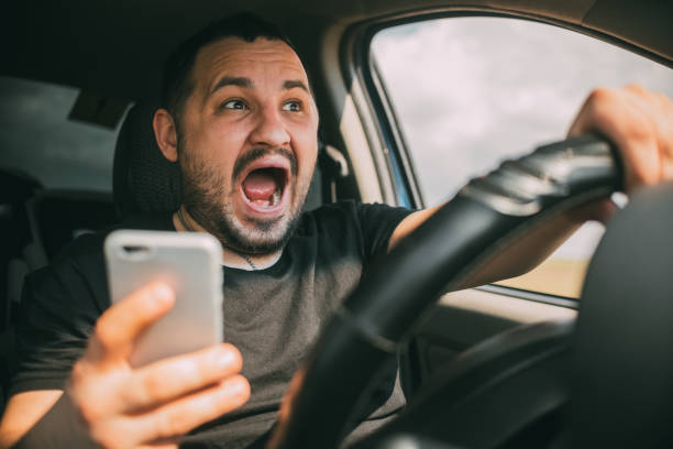 jeune homme s'asseyant dans sa voiture criant distrait par le smartphone - driving text messaging accident car photos et images de collection