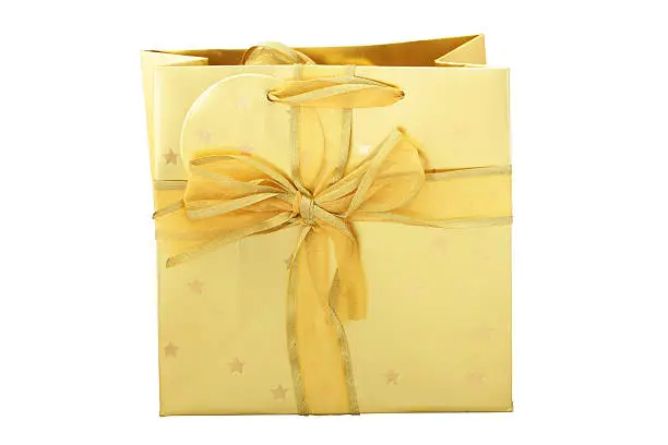 A golden paper giftbag isolated on white with bow and ribbon