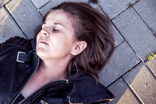 Young woman lying down on ground with eyes closed