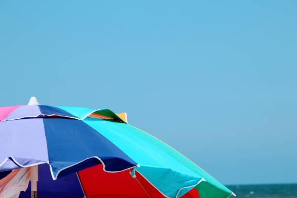 istock Colorful beach umbrella on sunny windy blue sky day . 1160072809