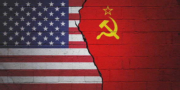 Cracked brick wall painted with a American flag on the left and a Soviet flag on the right.